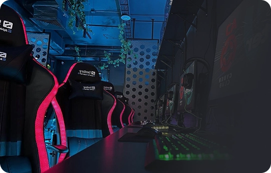 Slecht verlichte gameroom met groene toetsenborden en monitoren op een lang bureau. Ergonomische stoelen met rode accenten staan netjes op een rij. Futuristische sfeer.